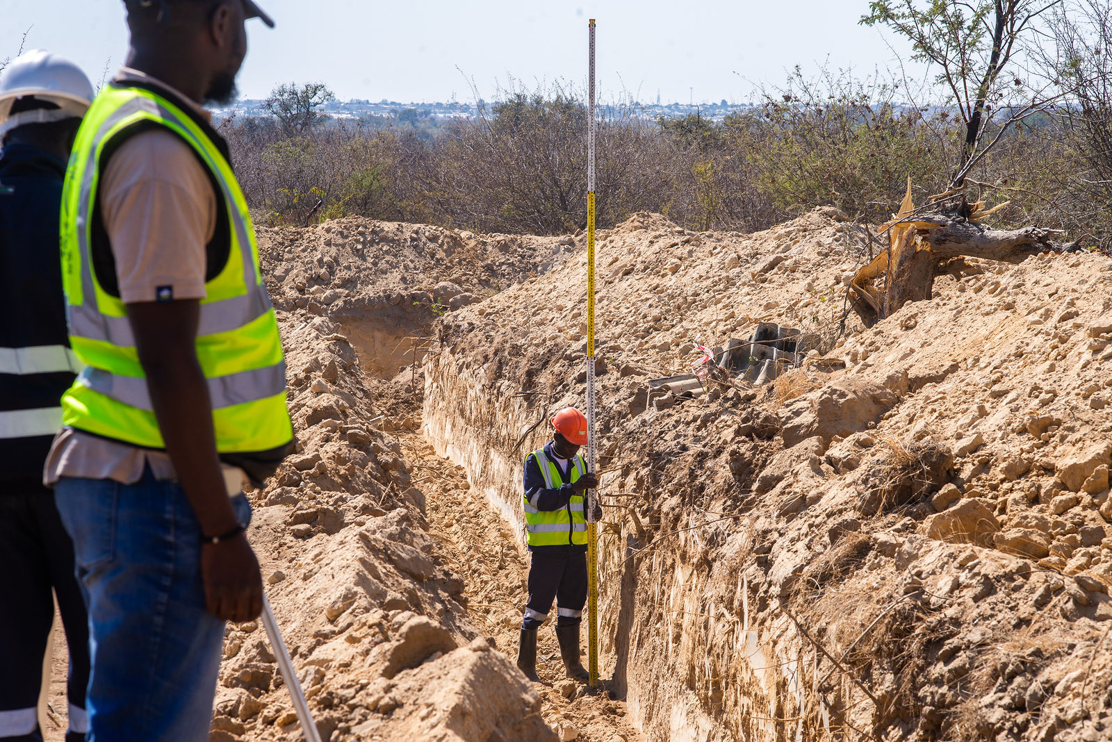 Survey team measuring trench works on site